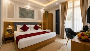 Habitación de hotel con cama, escritorio con fruta, silla, armario y ventilador de techo.