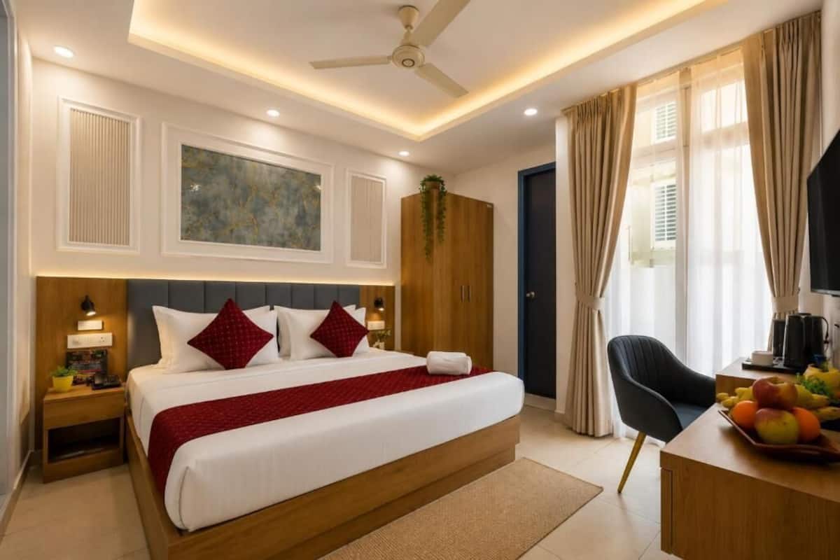 Habitación de hotel con cama, escritorio con fruta, silla, armario y ventilador de techo.