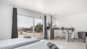 Une chambre d’hôtel moderne avec deux lits, une kitchenette et un balcon offrant une vue agréable.