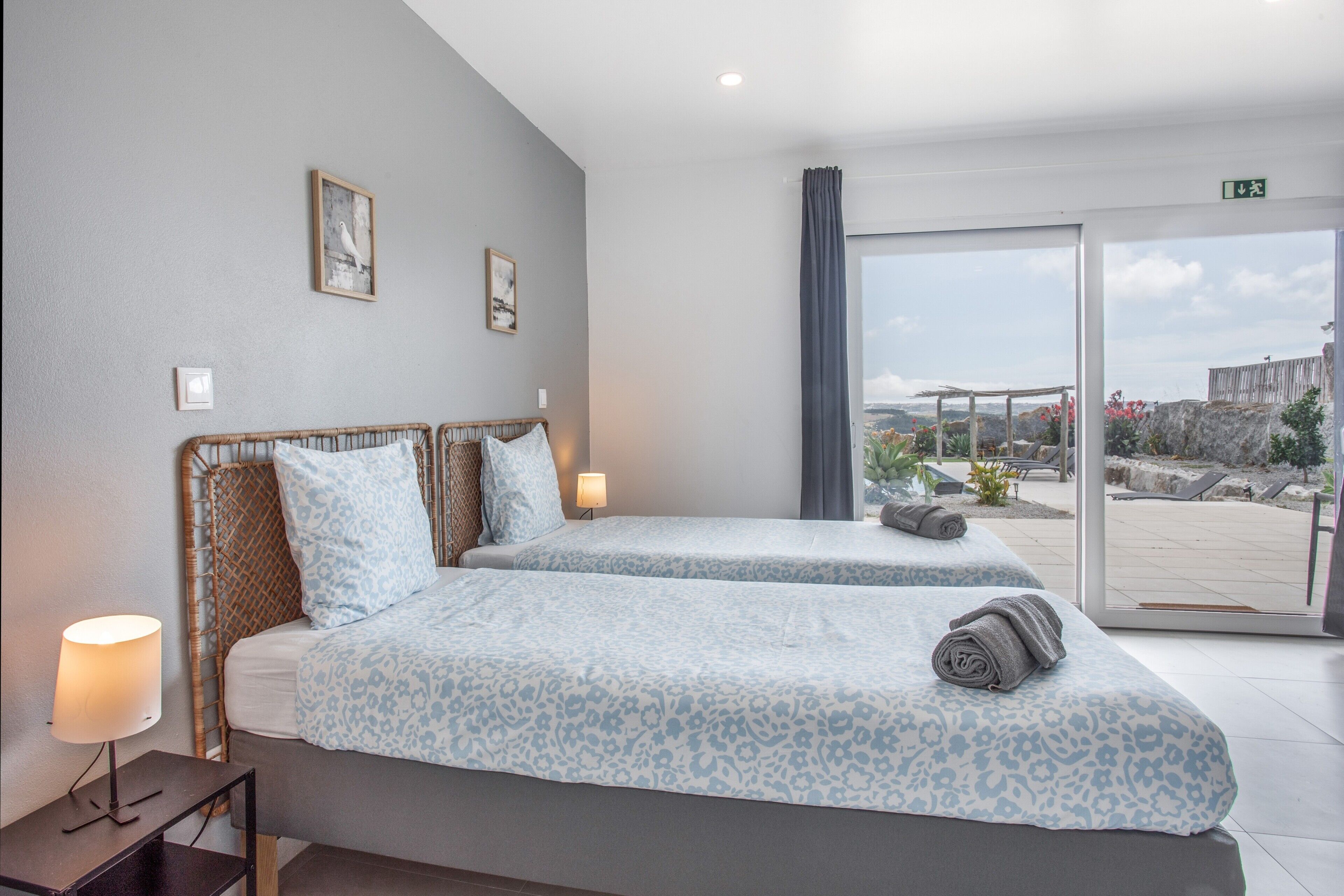 Une chambre d’hôtel avec deux lits, une table de chevet, une lampe et une vue sur l’extérieur.
