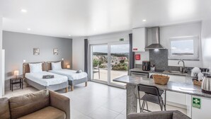 Une chambre d’hôtel moderne dotée de deux lits, d’une kitchenette, d’un coin repas et d’un balcon offrant une vue sur la ville.
