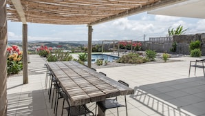 Une terrasse couverte avec une piscine, des sièges d’extérieur et une vue sur le paysage.