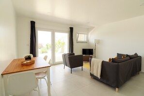 Una sala moderna con sofá, mesa de comedor, televisor y ventana.