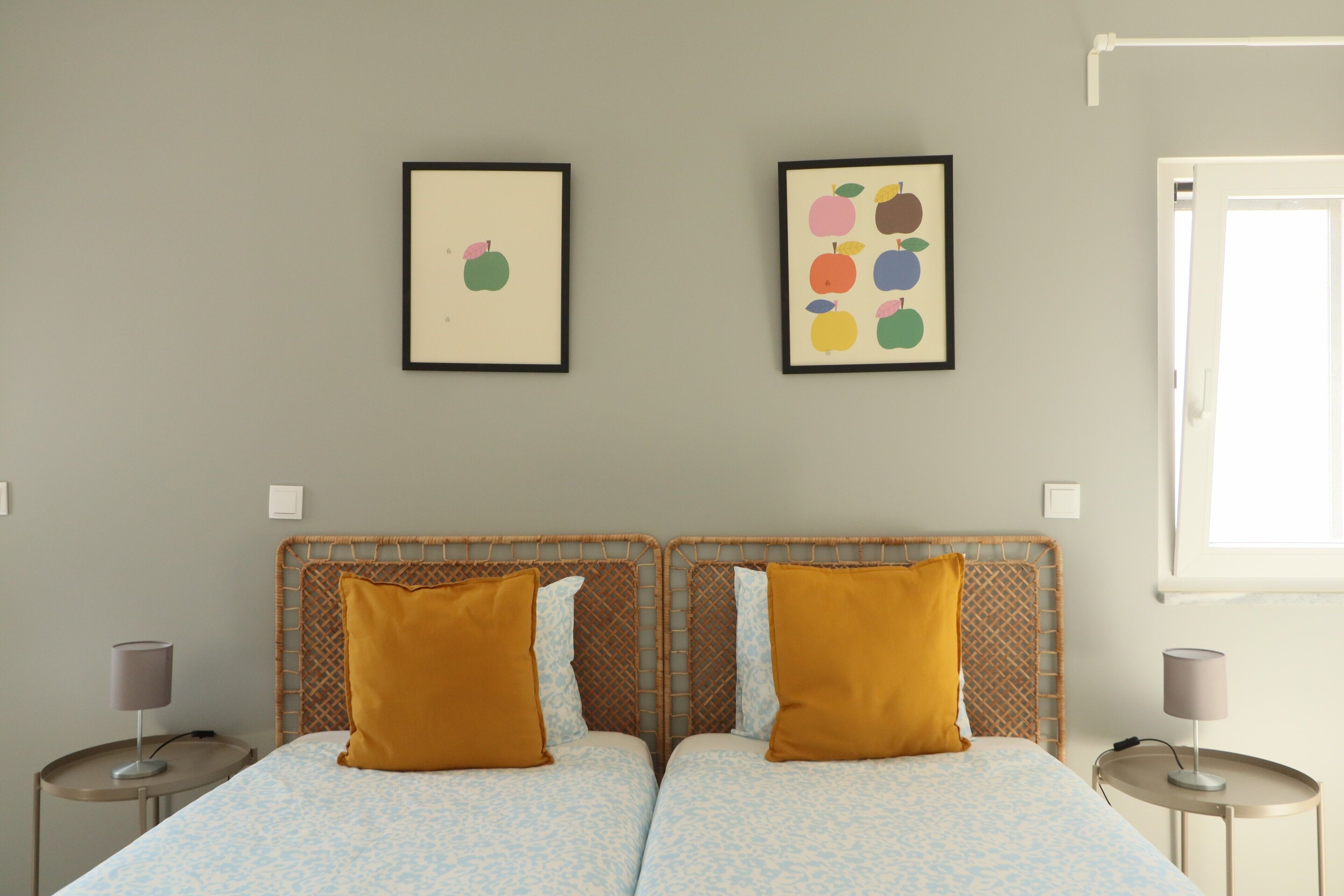 A double bed with two pillows, a bedside table, and a wall-mounted picture frame.
