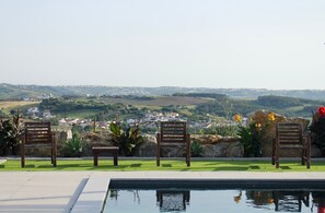Zona de piscina con sillas y vista a un pueblo distante.