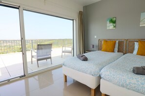 Ein Schlafzimmer mit zwei Betten, einem Balkon und Blick auf die Landschaft.