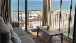 Ein Balkon mit Blick auf den Strand, einer Couch und einem kleinen Tisch.