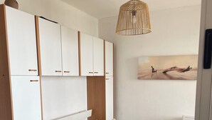 Ein Schlafzimmer mit Bett, Kleiderschrank, Pendelleuchte und einem Bild an der Wand.
