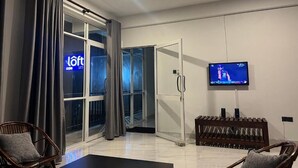 A modern hotel room with a sliding glass door to the outside, a flat-screen TV mounted on the wall, and a wooden bench. - Loft 123 - Kandy (Kandy)