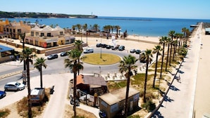 Eine Küstenstadt mit Kreisverkehr, Palmen, einem Strand und Meerblick.