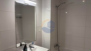 Ein Badezimmer mit Waschbecken, Spiegel, Dusche und Toilette.