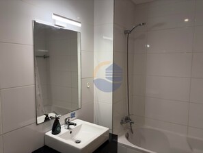 Ein Badezimmer mit Waschbecken, Spiegel, Dusche und Toilette.