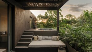 Un'area relax moderna all'aperto con panchina integrata, una piccola vasca idromassaggio e una scala che conduce a un edificio adiacente.