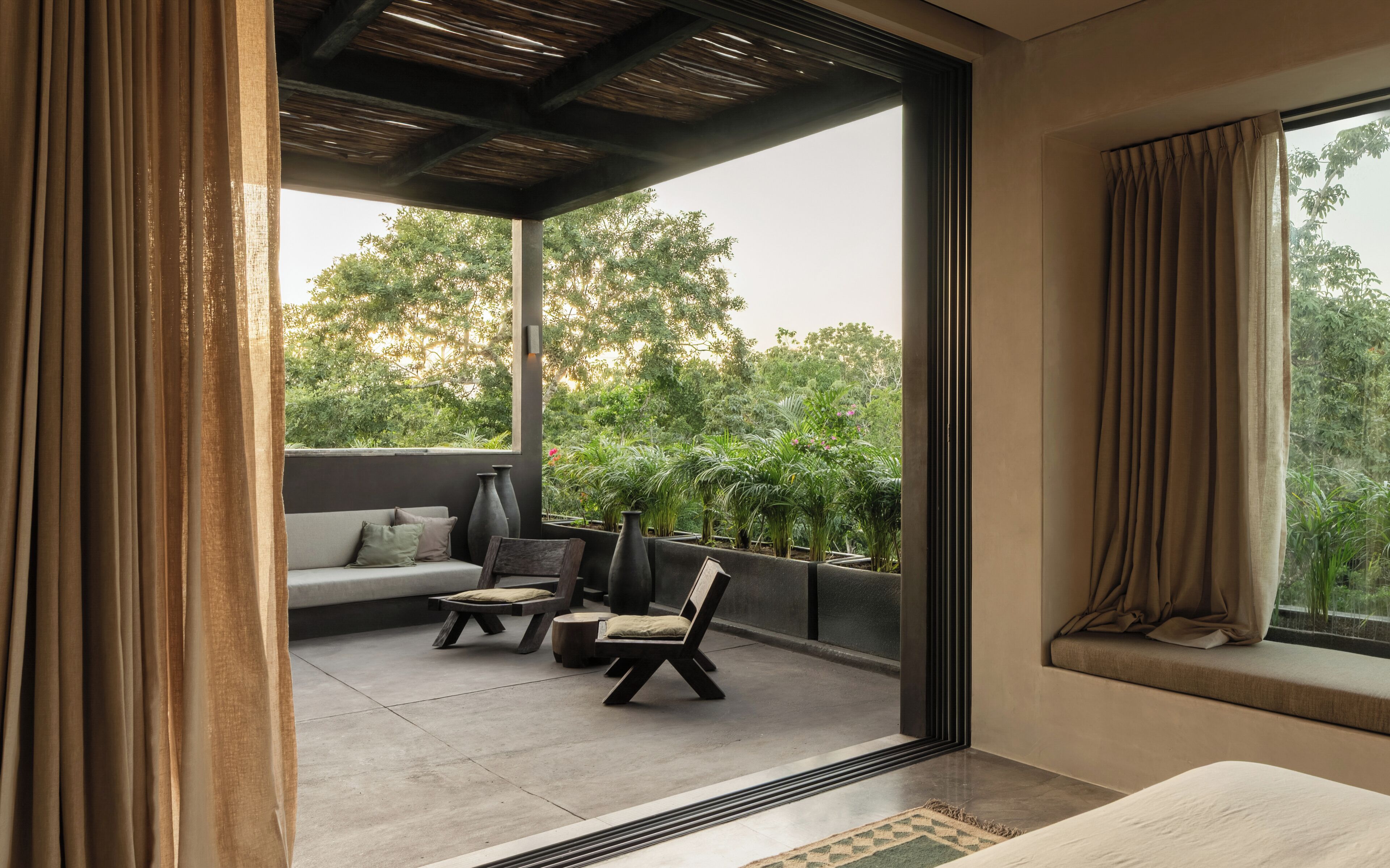 A modern room with a large sliding glass door leading to an outdoor patio. Inside, there is a sofa, two chairs, and a small table.