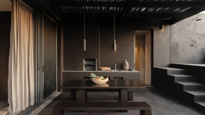 Un interno moderno con un tavolo da pranzo dalle tonalità scure, una ciotola di frutta e un design minimalista.
