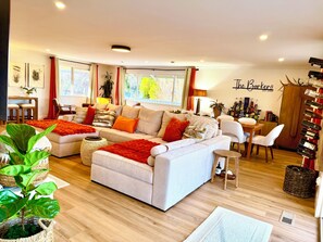 A modern living room with a sofa, a dining area, and a wine rack.