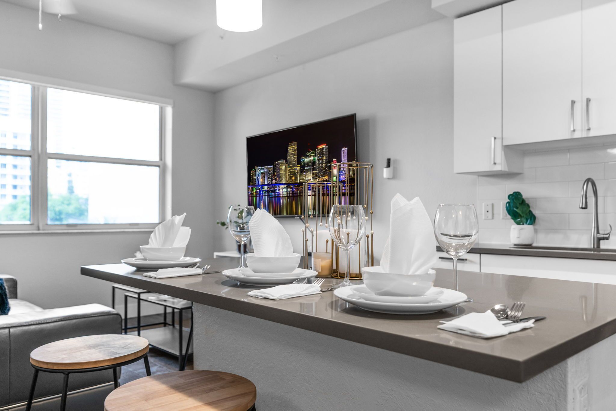 Una cocina moderna con una isla central, armarios blancos y vistas a un paisaje urbano.