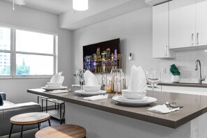 Una cocina moderna con una isla central, armarios blancos y vistas a un paisaje urbano.