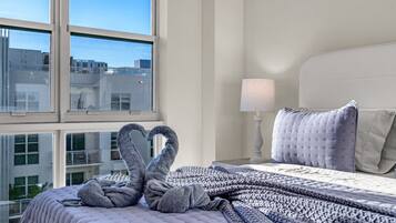 Habitación de hotel con cama, ventana y vistas a edificios.