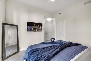 A bedroom with a bed, a mirror, a cityscape painting, and a door. - Blu Apartments (Miami)