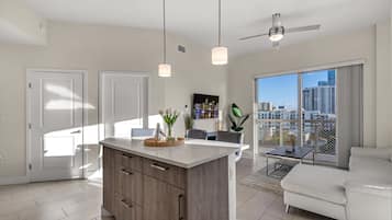 Un apartamento moderno con isla de cocina, comedor y balcón con vistas a la ciudad.