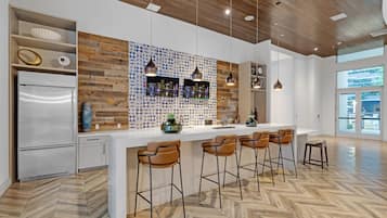 Una cocina moderna con protector de salpicaduras de madera, un refrigerador de acero inoxidable y una zona de bar con taburetes.