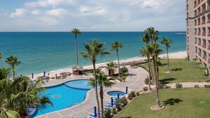 Un resort con piscina, palmeras y vista al océano.