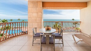 Un balcón con vista al mar, una piscina y una mesa con sillas.