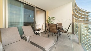 Un balcon avec des fauteuils de jardin, une petite table et un pot de fleurs.