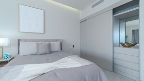 Ein modernes Schlafzimmer mit Bett, Nachttisch mit Lampe, großem Spiegel und Schiebetürenschrank.