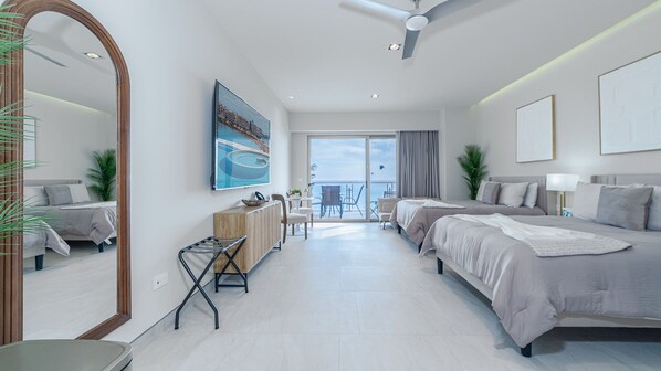 Une chambre d’hôtel moderne avec deux lits, un coin repas, un grand miroir et un balcon avec vue.