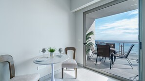 Un balcon avec une table, des chaises et une vue sur l’océan.