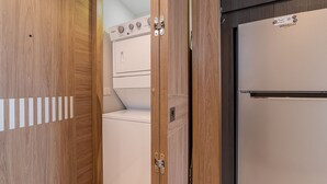 Une petite buanderie équipée d’un lave-linge et d’un sèche-linge, de meubles en bois et d’un réfrigérateur Whirlpool.