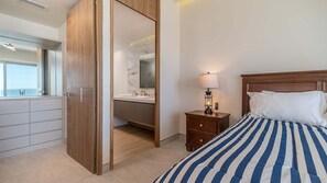 A bedroom with a bed, bedside table, lamp, and a view of the bathroom. - Luxury Beachfront Escape With Stunning Ocean Views (Puerto Peñasco)