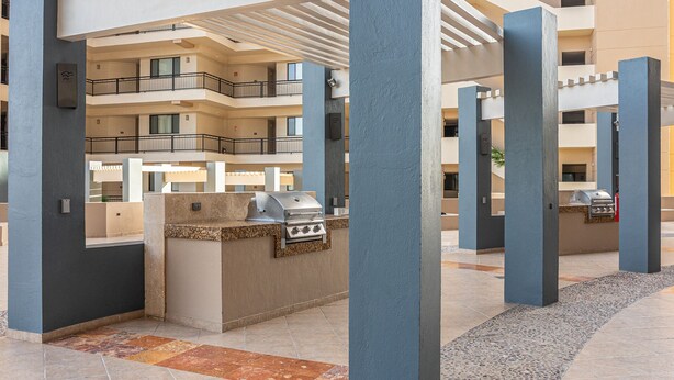 Area patio esterna con una griglia per barbecue, circondata da colonne e un porticato.