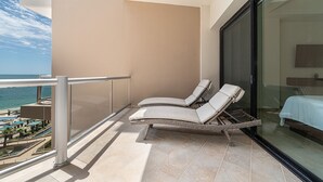 Un balcone con due poltrone, una porta vetrata che dà su una camera da letto e vista sull'oceano.
