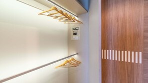 Ein Flur mit hölzernen Kleiderbügeln an der Wand, einer Bedienkonsole und einer Holztür mit geometrischem Muster.