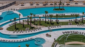 Ein großer, mehrstöckiger Pool mit Liegestühlen und Palmen.