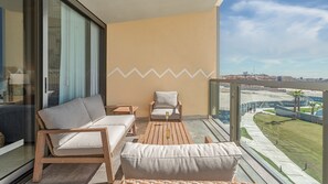 Ein Balkon mit einer Couch, Stühlen und einem Tisch mit Blick auf eine Stadtlandschaft.