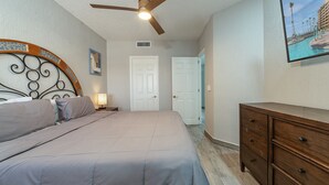 Une chambre à coucher avec un lit, une commode, un ventilateur de plafond et une porte.