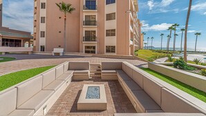 Une cour d’hôtel avec des espaces de détente en plein air, une piscine et une vue sur l’océan.