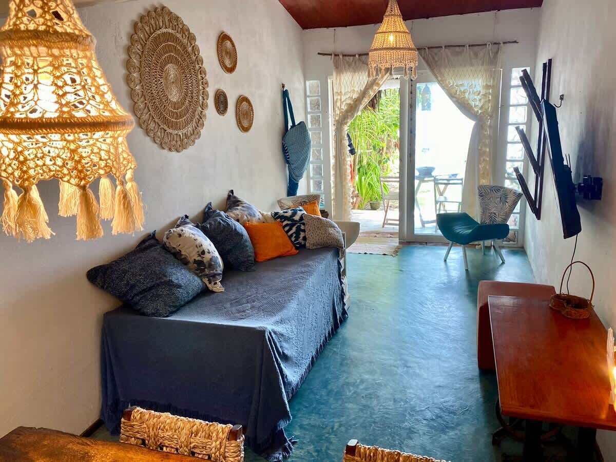 Une pièce comprenant un lit, une table et une chaise. Les murs sont décorés et une lampe est suspendue au plafond.