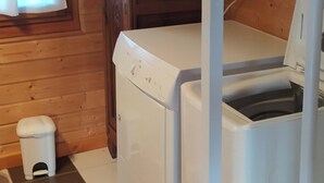 A laundry room with a washing machine, a dryer, and a small trash bin.