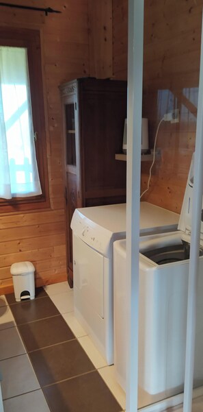 A laundry room with a washing machine, a dryer, and a small trash bin.