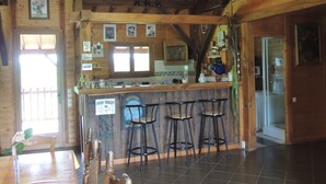 A rustic wooden interior with a bar area, wooden beams, and tiled flooring.