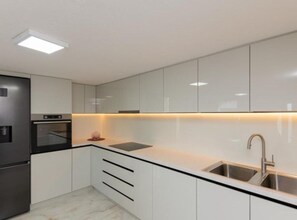 A modern kitchen with white cabinets, a black refrigerator, a built-in oven, and a stainless steel sink. - Villa Ante With Outdoor Pool (Imotski)