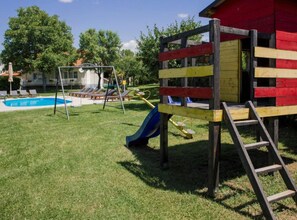 A playground with a slide and swings, a pool, and a red and yellow playhouse. - Villa Ante With Outdoor Pool (Imotski)