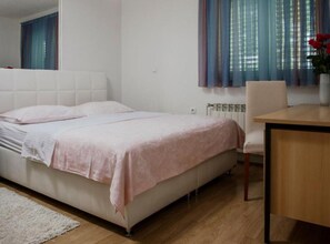 Ein Schlafzimmer mit Bett, Stuhl, Tisch und Heizkörper.