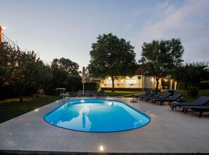 Ein schwimmender Pool mit runder Form, umgeben von Liegestühlen und einem Gebäude im Hintergrund.