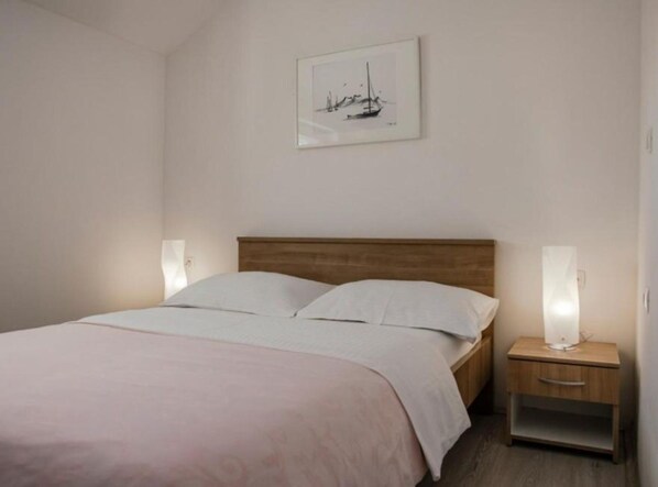 A neatly made bed with a wooden headboard, a bedside table with a lamp, and a framed picture on the wall. - Villa Ante With Outdoor Pool (Imotski)